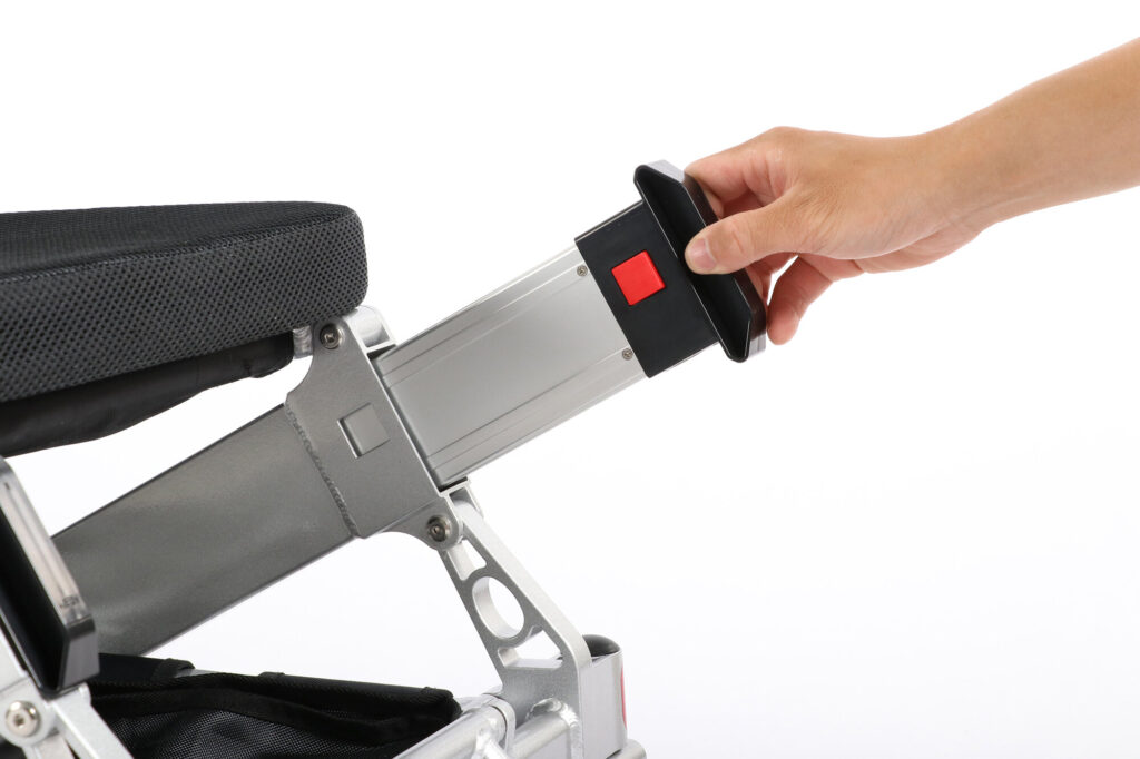 Porto Mobility Ranger Maestro XL reclining folding power wheelchair, hand holding a pack with red button at the frame tube end under the seat