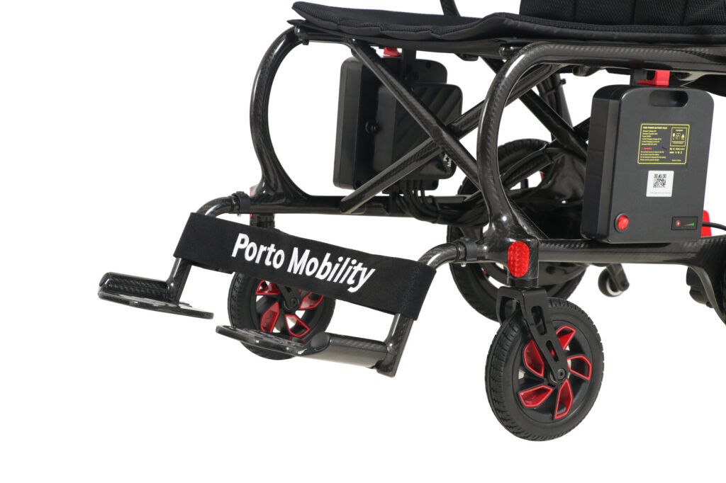 Porto Mobility Ranger Aero folding power wheelchair, close up of front casters, footplates and leg strap