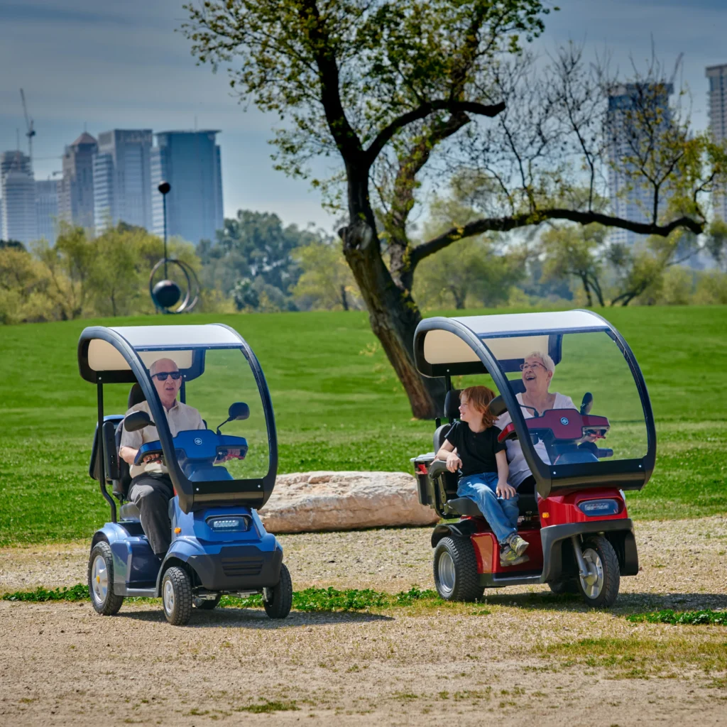 Lifestyle Image Side View of Blue Afiscooter S4 with Canopy Mobility Scooter, Red Afiscooter S3 Dual Seat Mobility Scooter with Canopy Golf Tires